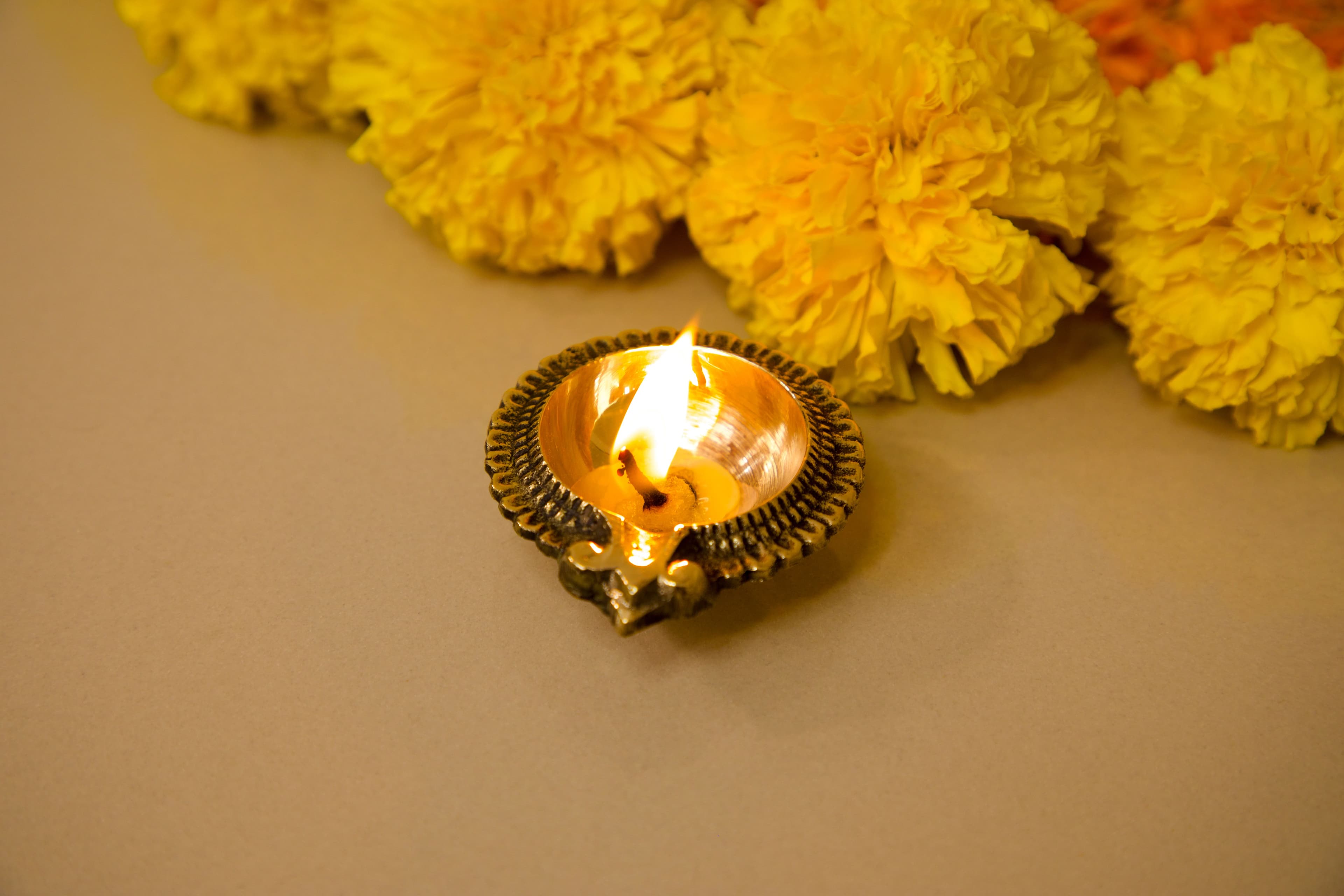 Glowing brass diya with yellow flowers